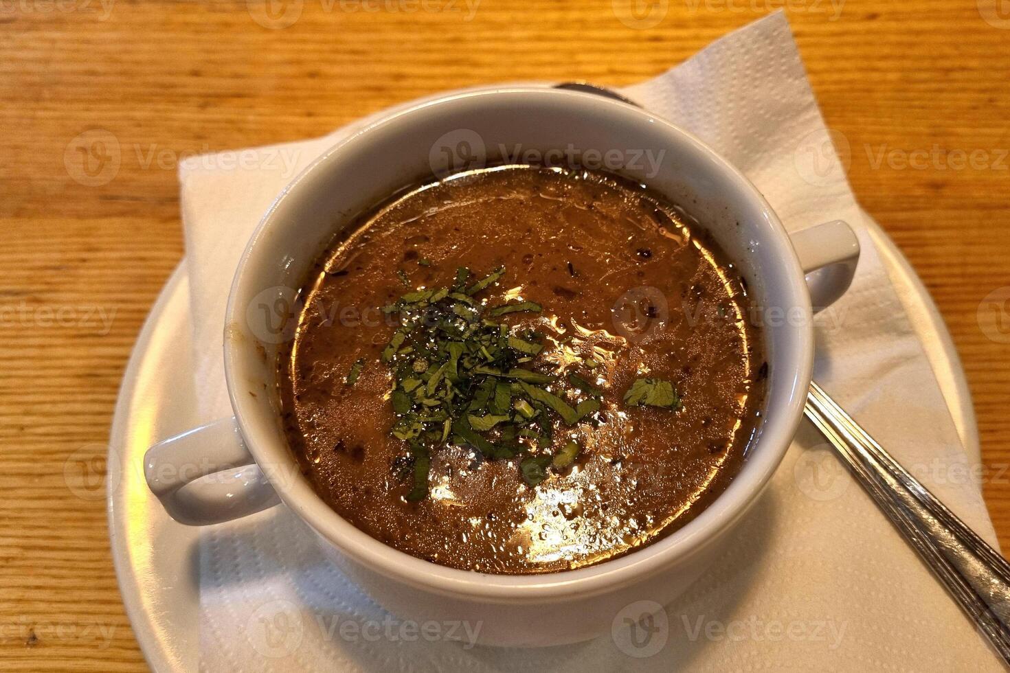 Hearty Mushroom Soup in White Bowl on Wooden Table with Garnish photo