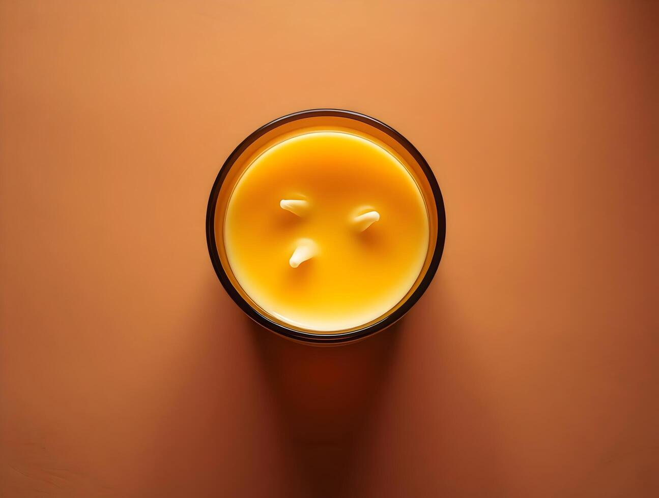 A candle is shown on a brown surface photo
