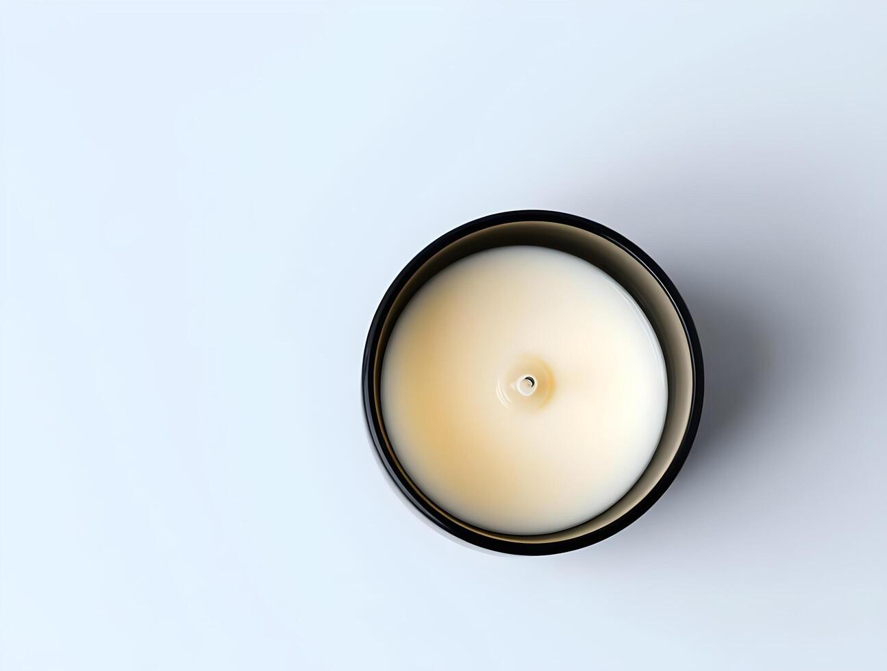A candle in a black bowl on a white surface photo