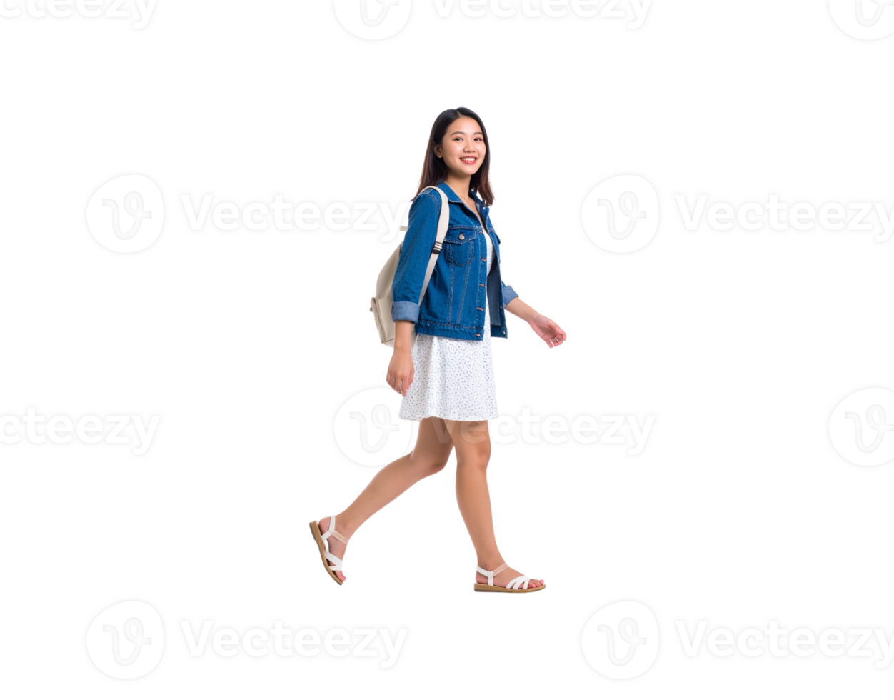 Smiling young Asian woman in a denim jacket and sundress walking with a white backpack. png