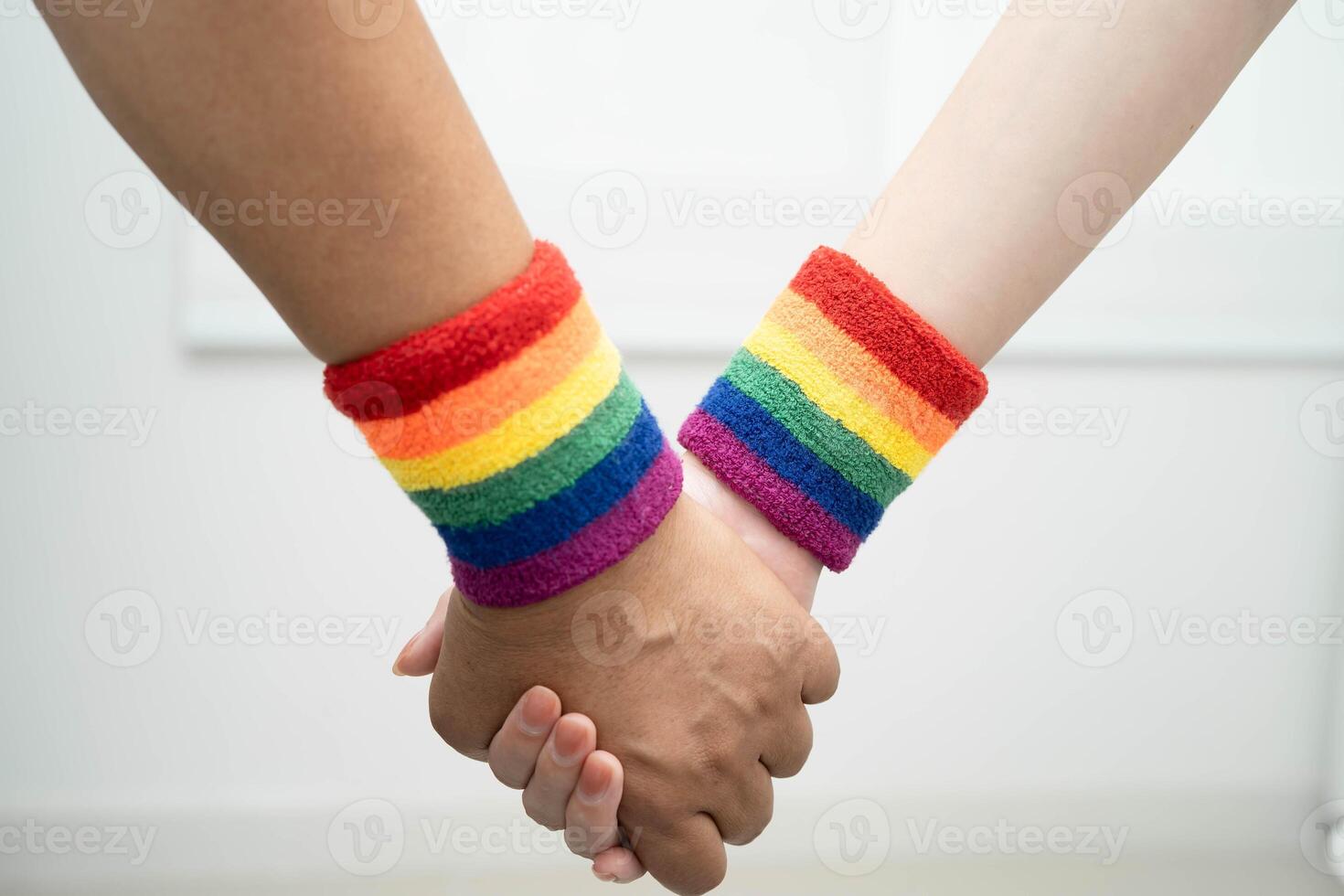 LGBT couple woman holding hand wearing wristband. photo