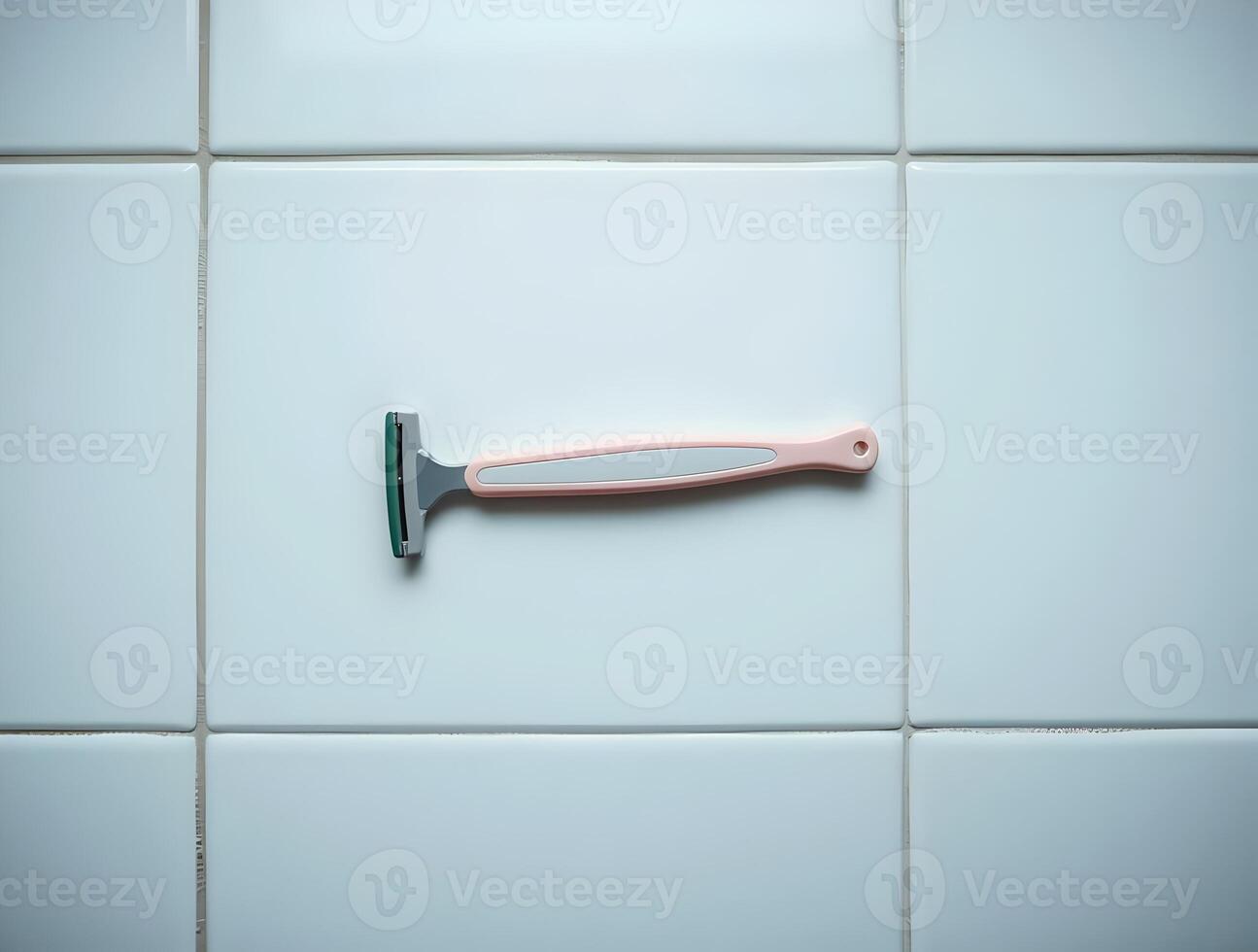 A razor is sitting on a tiled wall photo