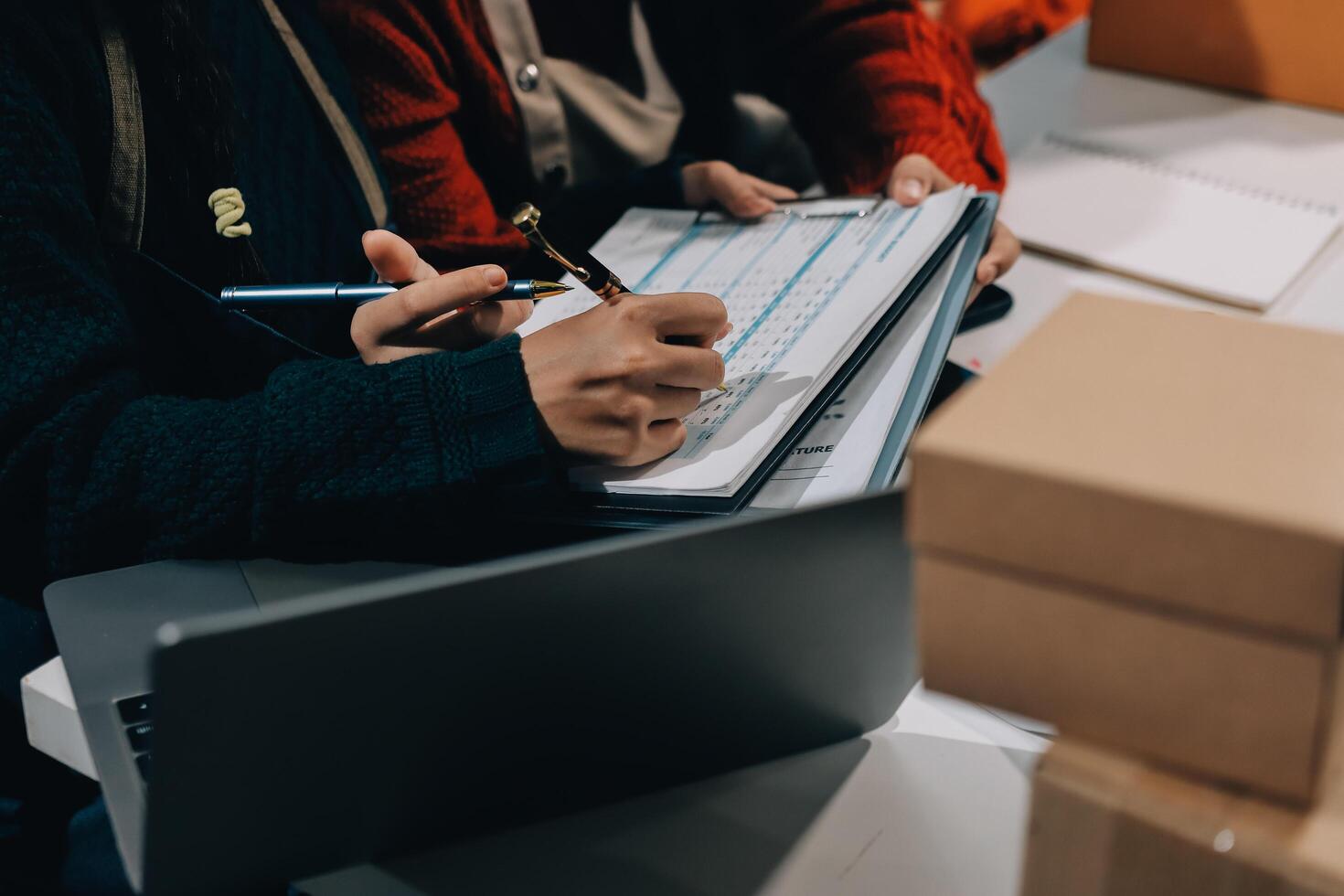 Two people working on a laptop with boxes around them photo