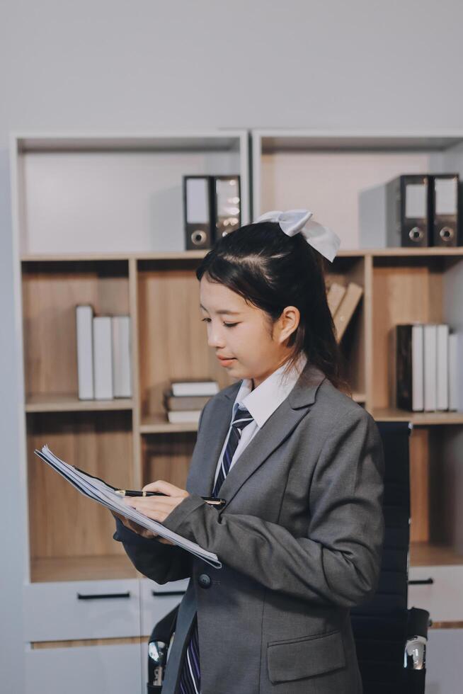 Asian female student in business suit writing on a clipboard photo