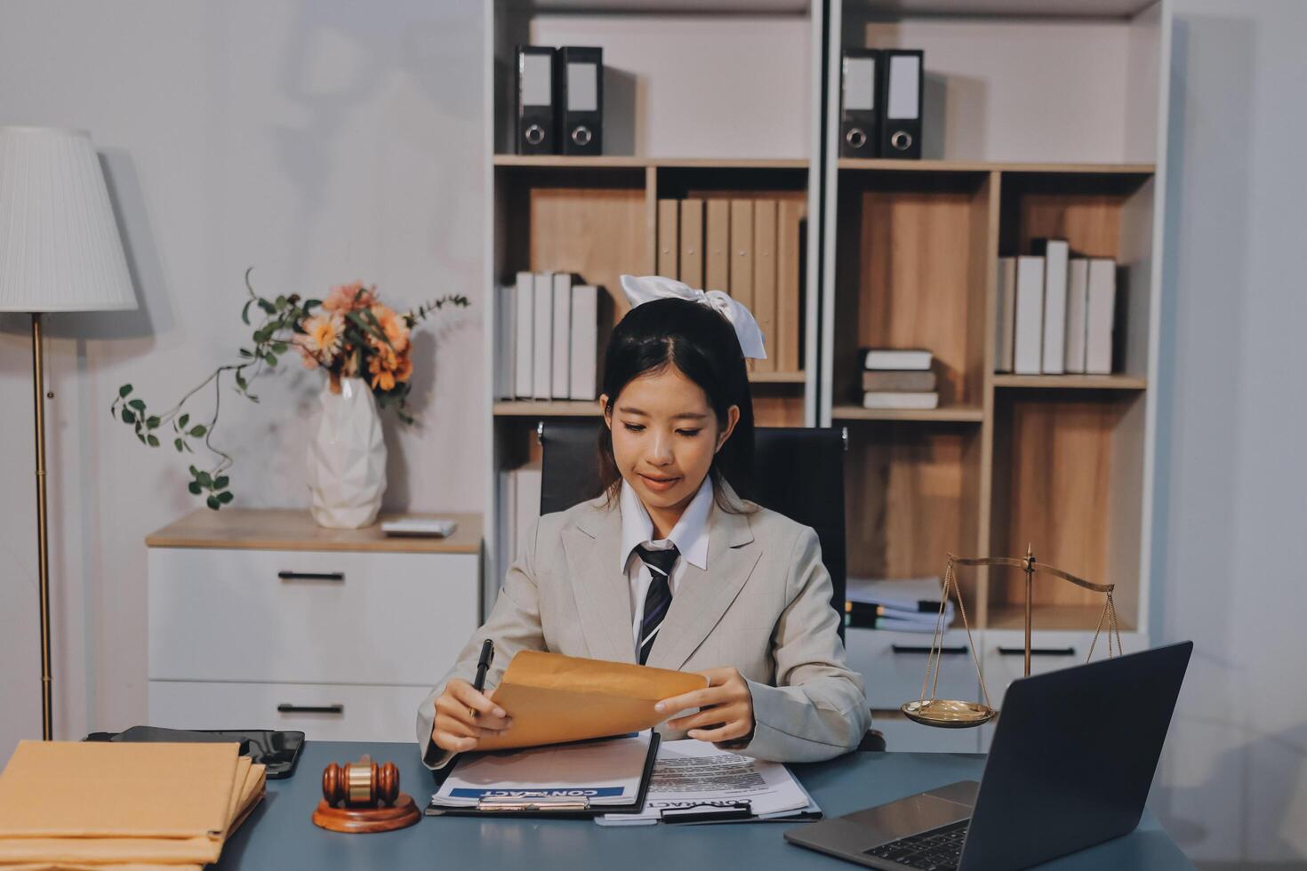 Asian woman in business suit sitting at desk with laptop photo