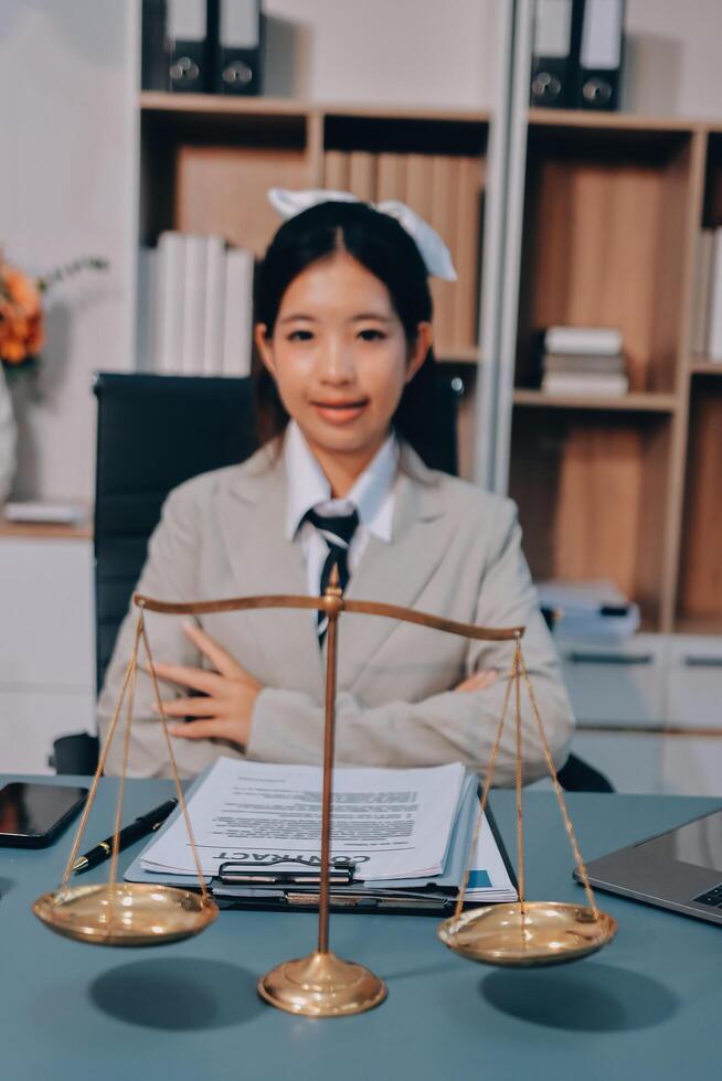 Asian female lawyer sitting at desk with scales of justice photo