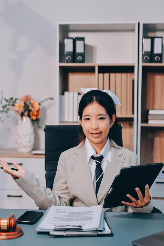 Asian female lawyer sitting at desk with tablet and laptop photo