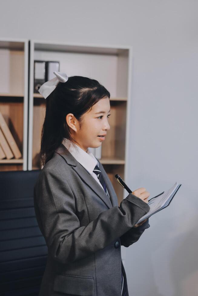 Asian girl in business suit writing on a notepad photo