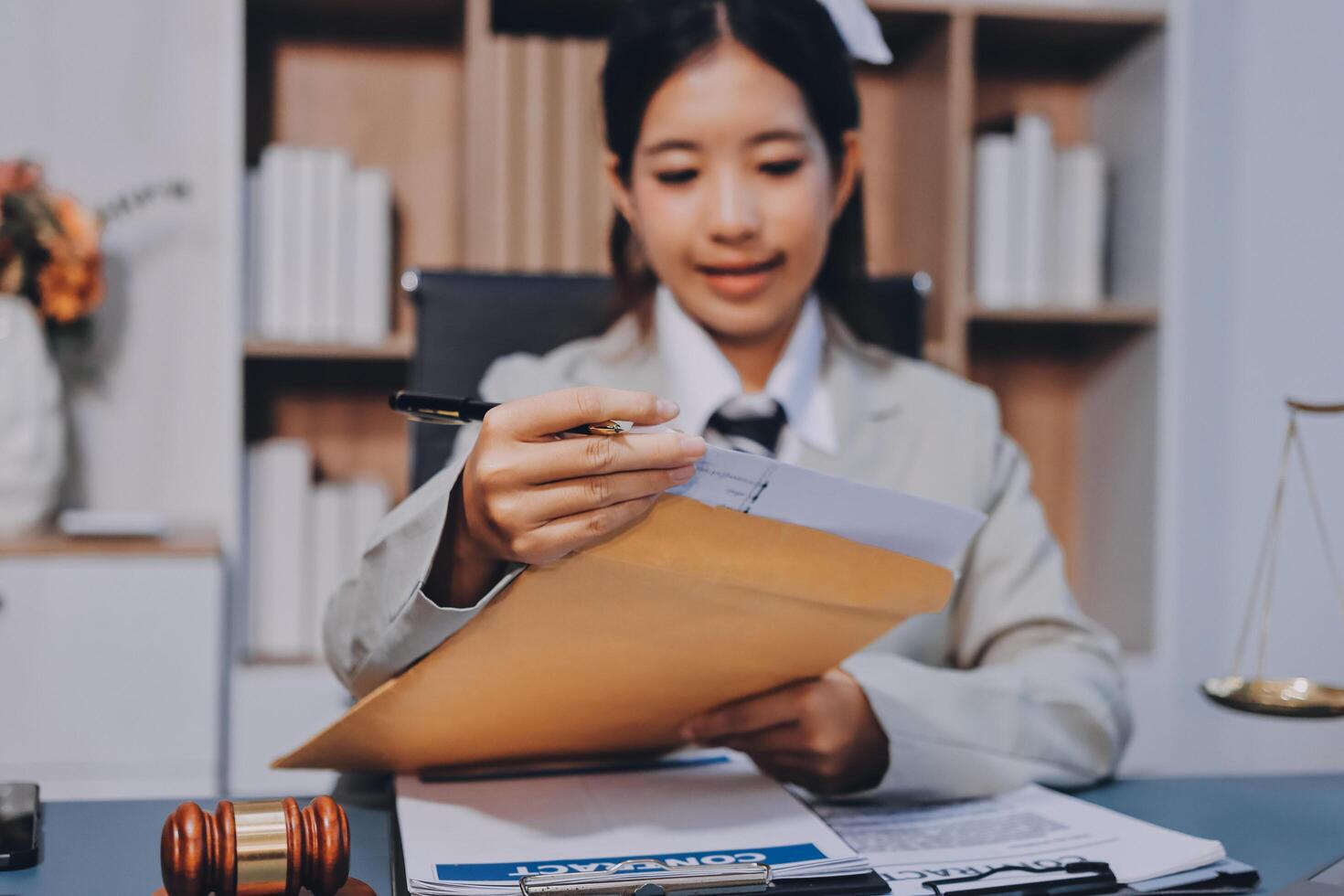 A woman in a business suit is holding a folder and looking at a document photo