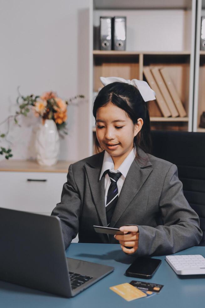 Asian girl in business suit using laptop and credit card photo