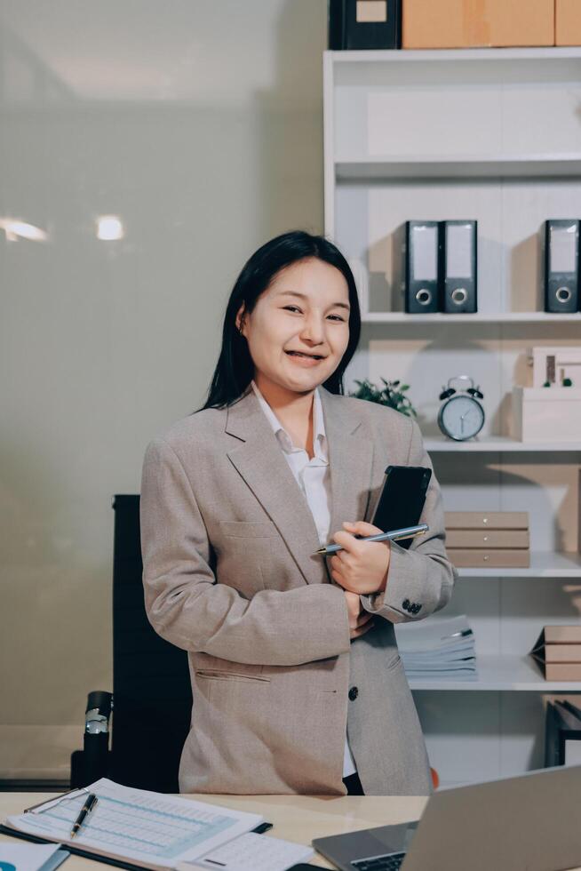 Asian business woman standing in office with laptop and phone photo