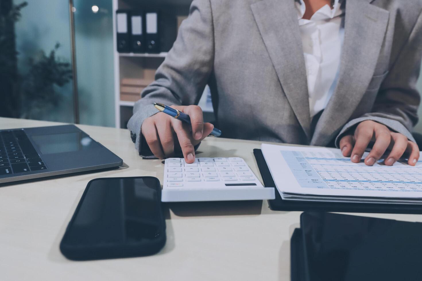 A woman in a suit is working on a calculator photo