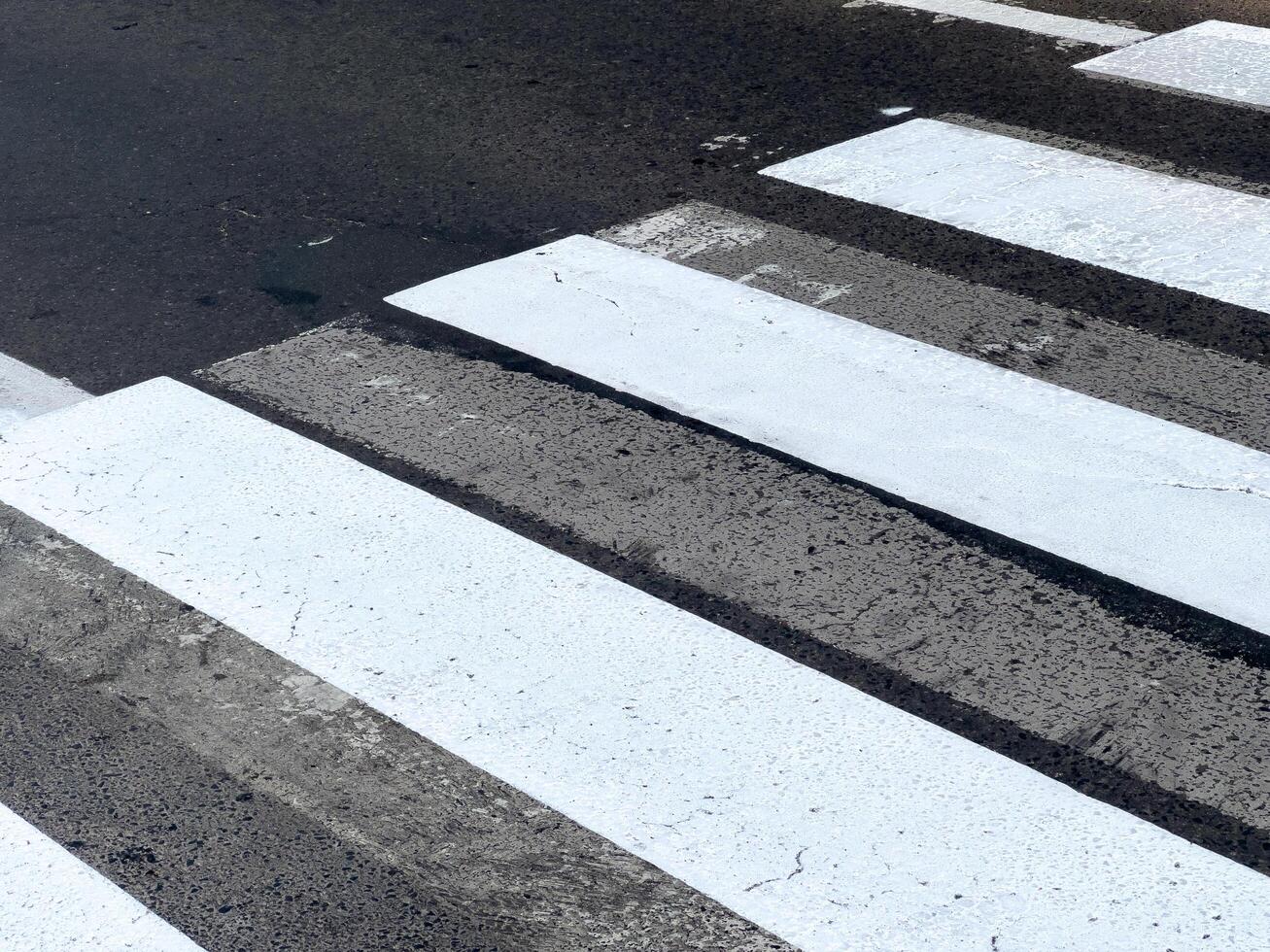 Freshly painted pedestrian crossing lines create a clear path for walkers in a lively urban setting during daylight hours photo