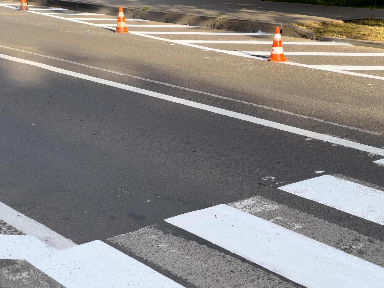 Traffic cones are placed on a freshly painted crosswalk in a city street under clear skies, marking safe pedestrian passage photo