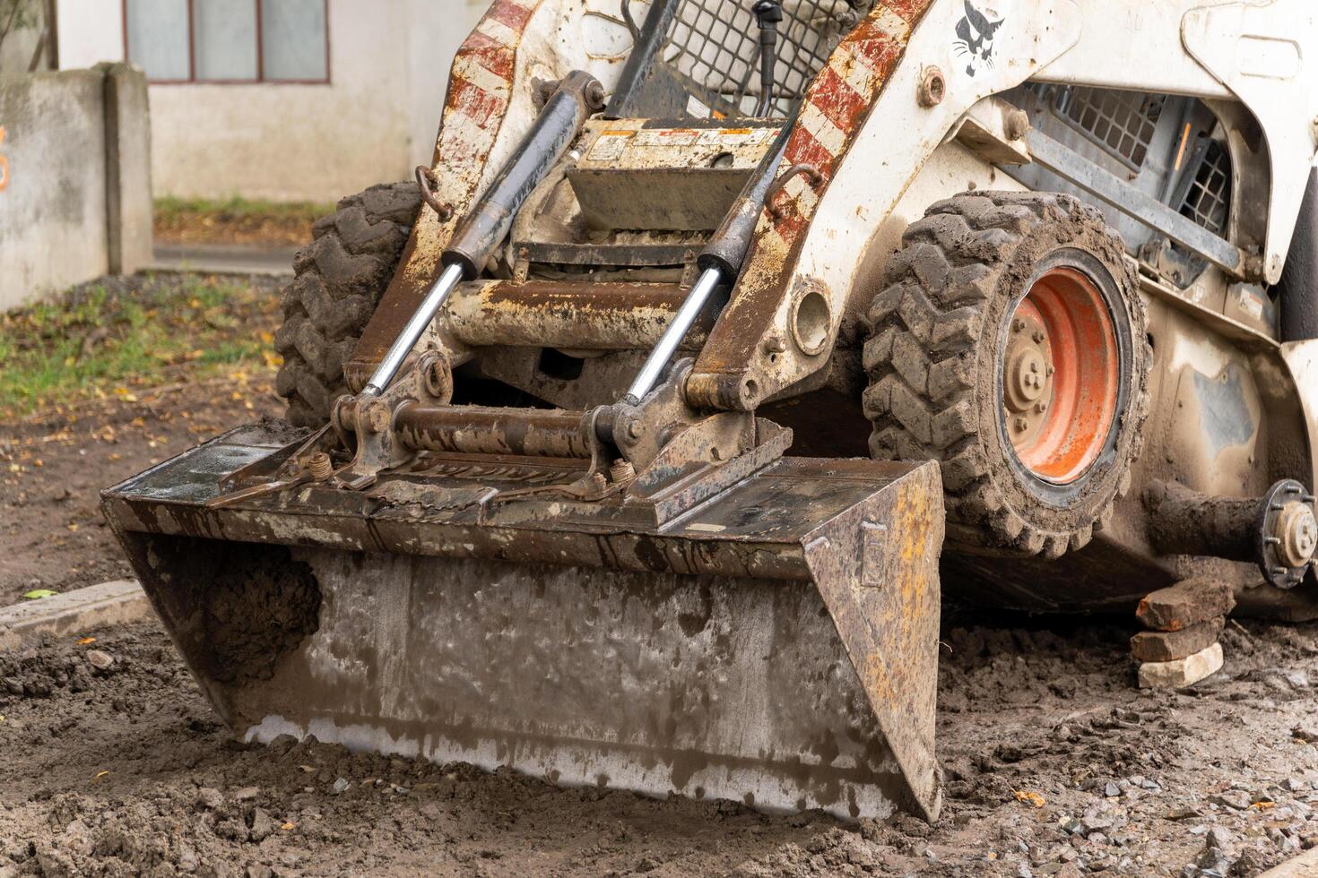 Heavy machinery clears muddy ground in an urban location during an autumn work project, showcasing construction activity in progress photo