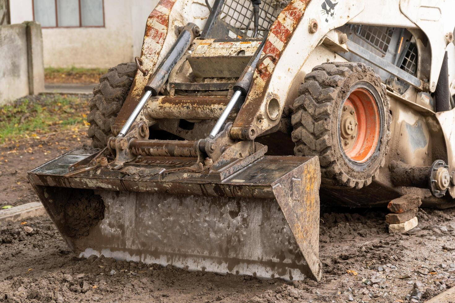 A skid steer is prepping the ground at a construction site nestled in nature, signaling ongoing development photo