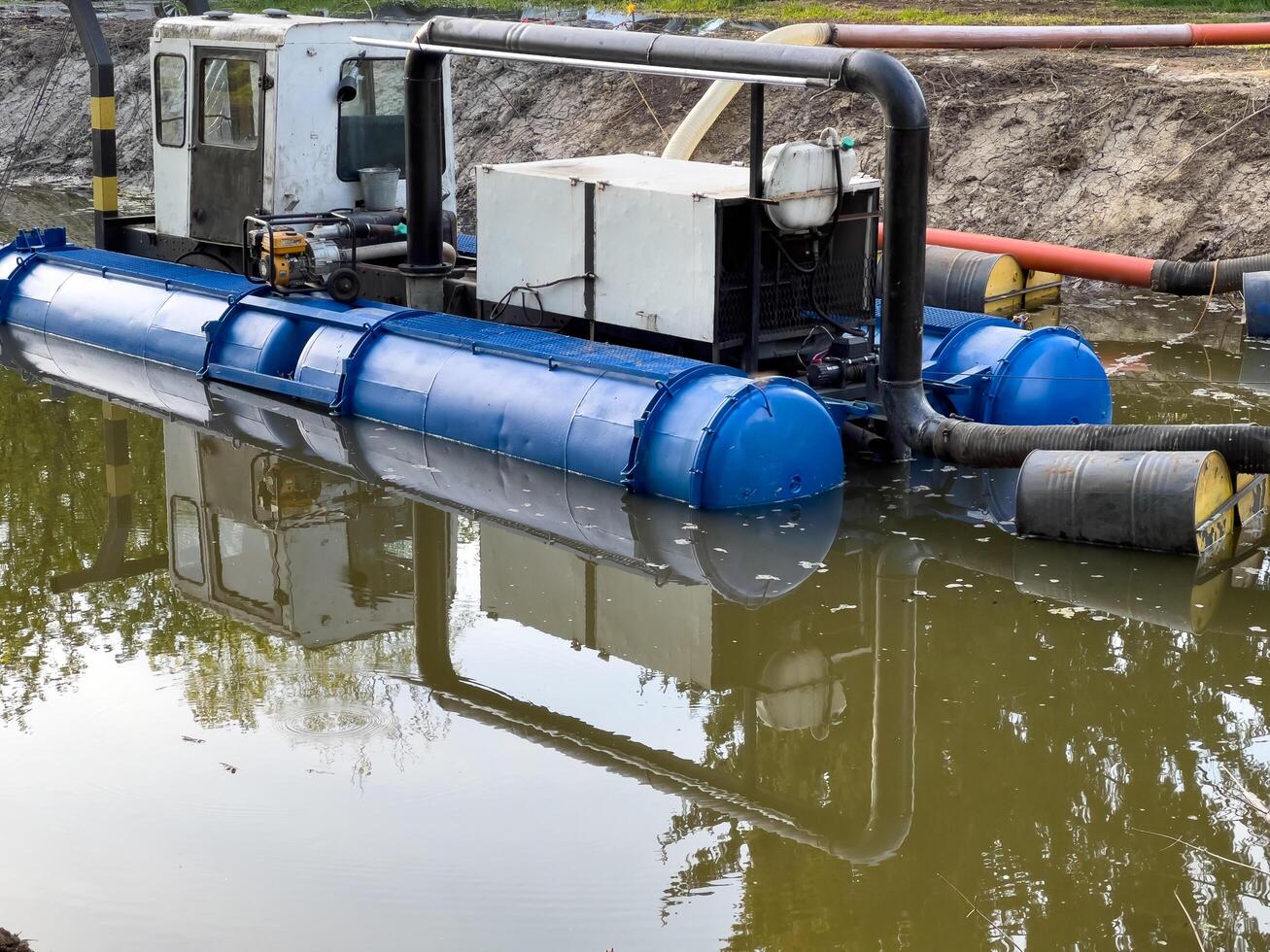 Heavy machinery works on a waterway to clear sediment and improve water quality, reflecting its structure in the calm surface photo