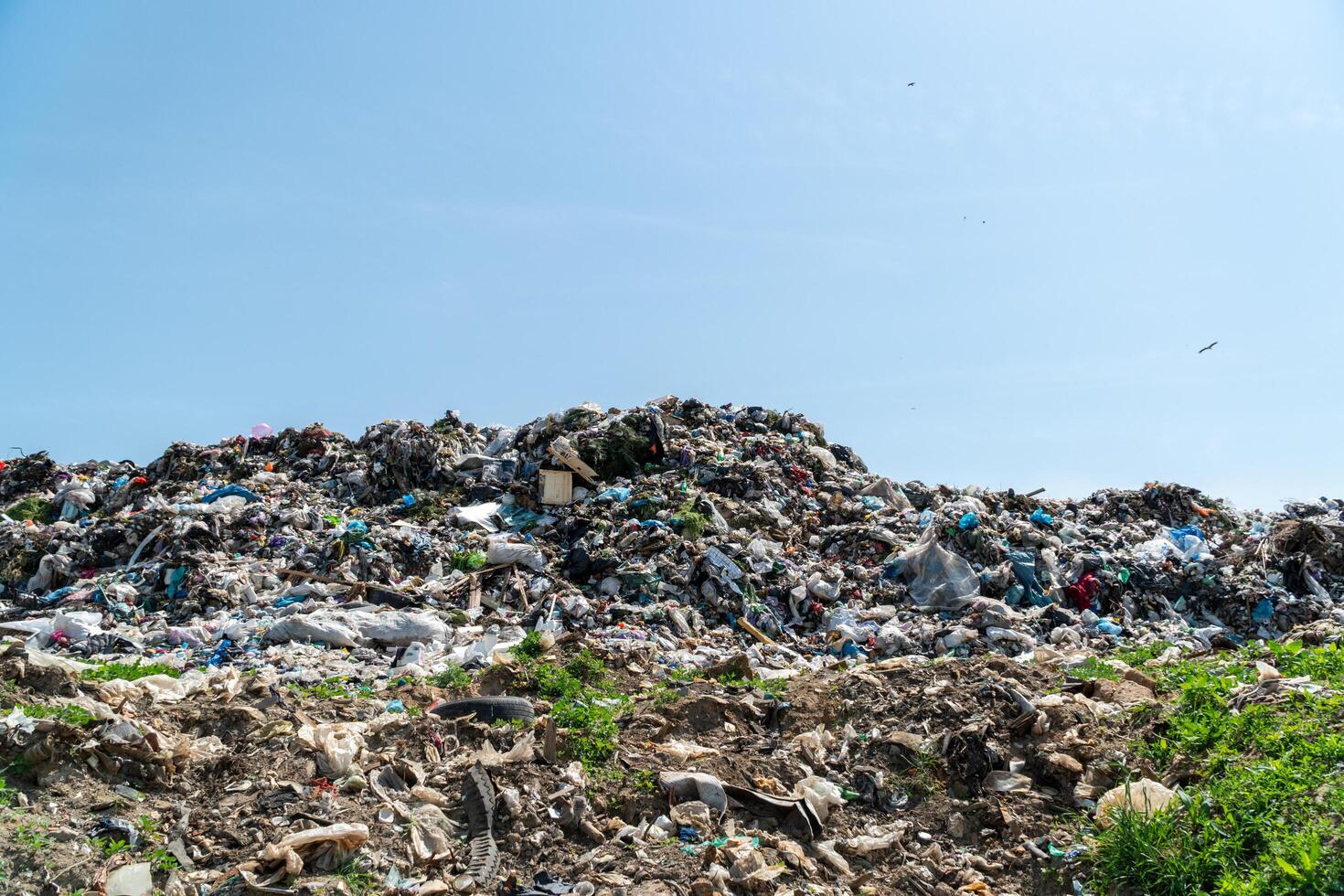 A massive pile of waste sits in a landfill under a blue sky, raising concerns about the environment and waste management photo