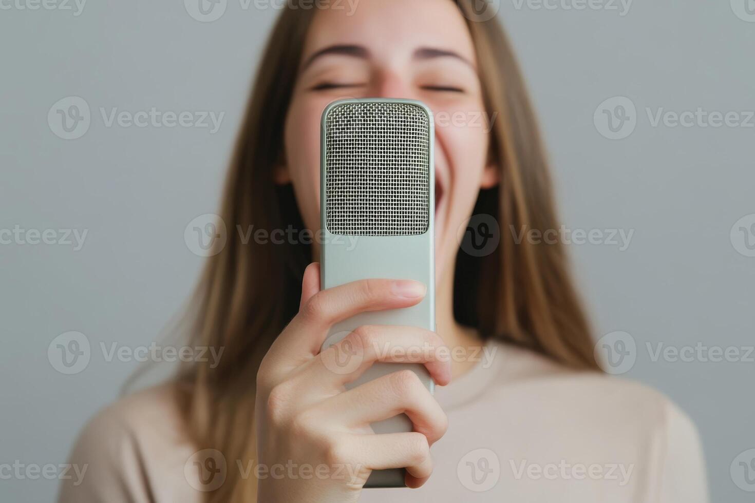 Woman enjoying singing into a microphone with a joyful expression in a minimalistic indoor setting photo