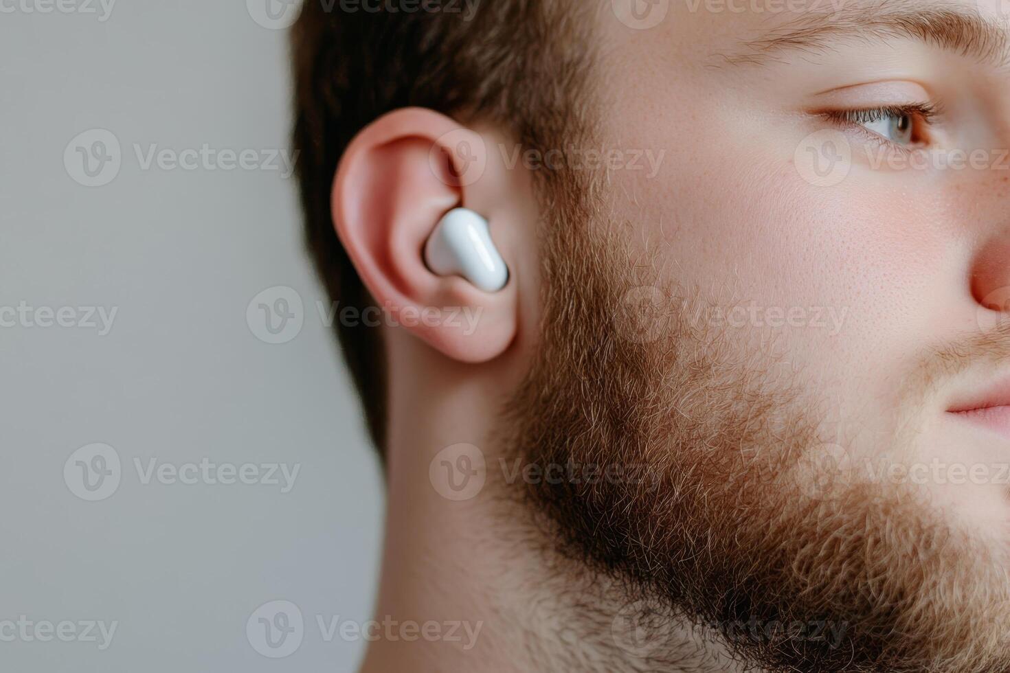 Young man wearing wireless earbuds while enjoying music at home in a cozy environment with natural light photo
