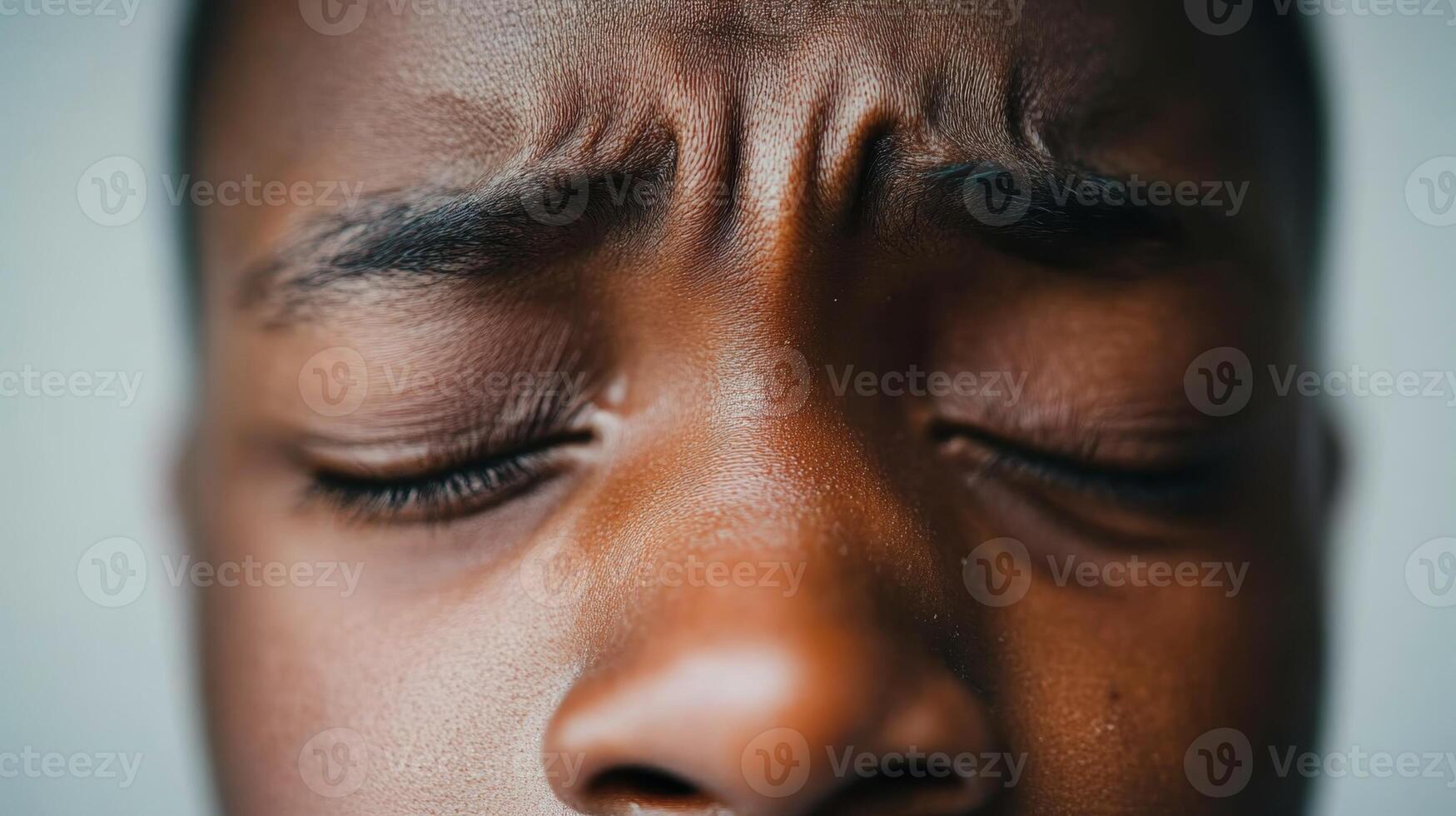 Close-up of a young person's face showing emotions with tightly shut eyes and furrowed brow highlighting expressions of frustration or concentration photo