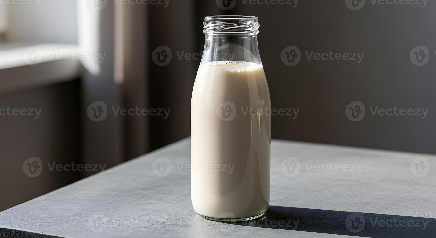 A glass bottle of milk sitting on a table photo