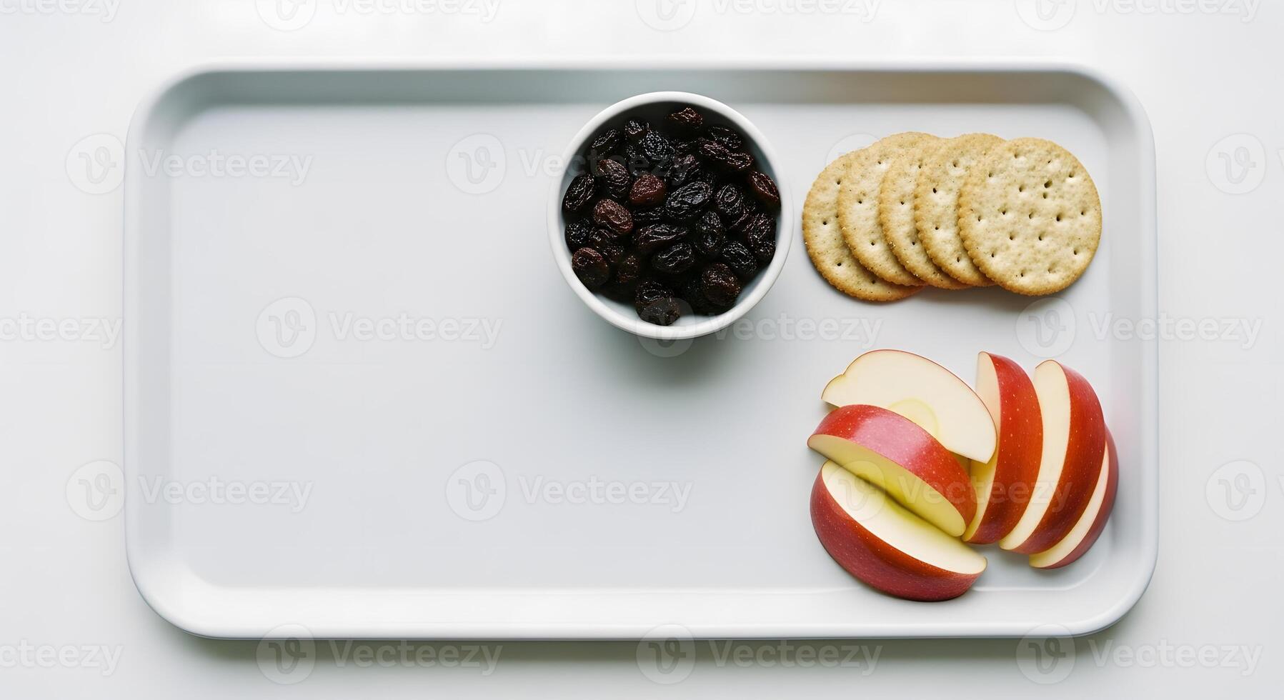 A tray with crackers, apples, and raisins photo