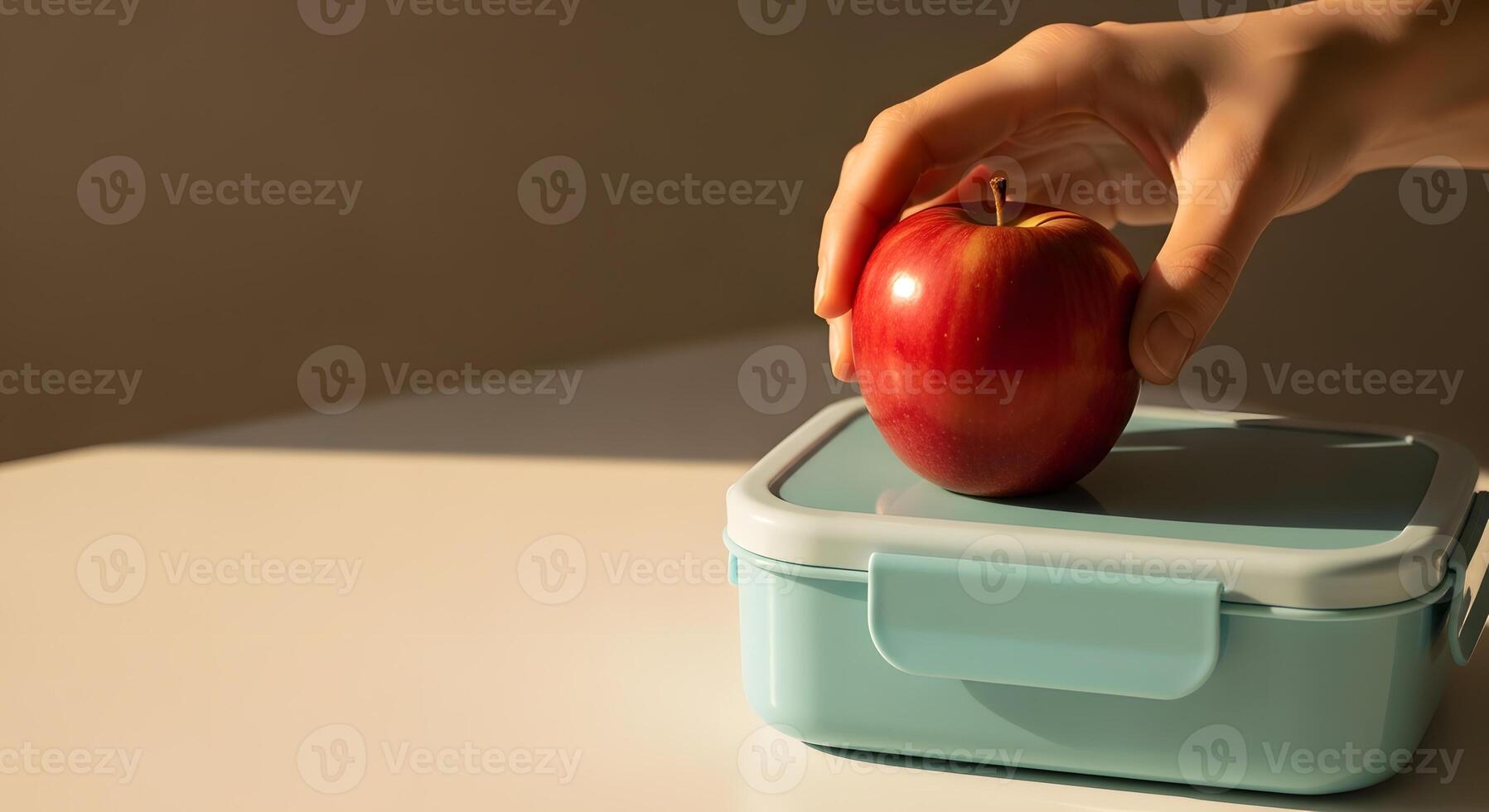 A person is holding an apple in front of a lunch box photo