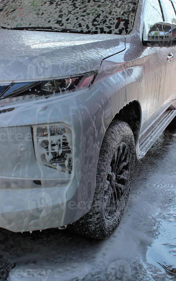 White SUV On Car Wash Station Under Cleaning Foam photo