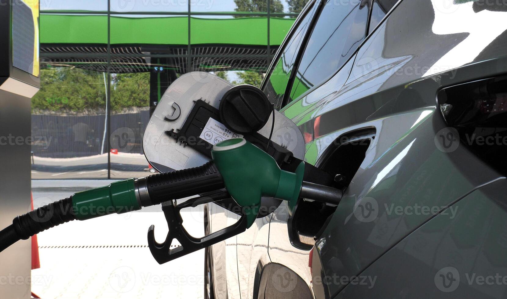 Refueling nozzle inserted into the car gas tank neck rear view photo