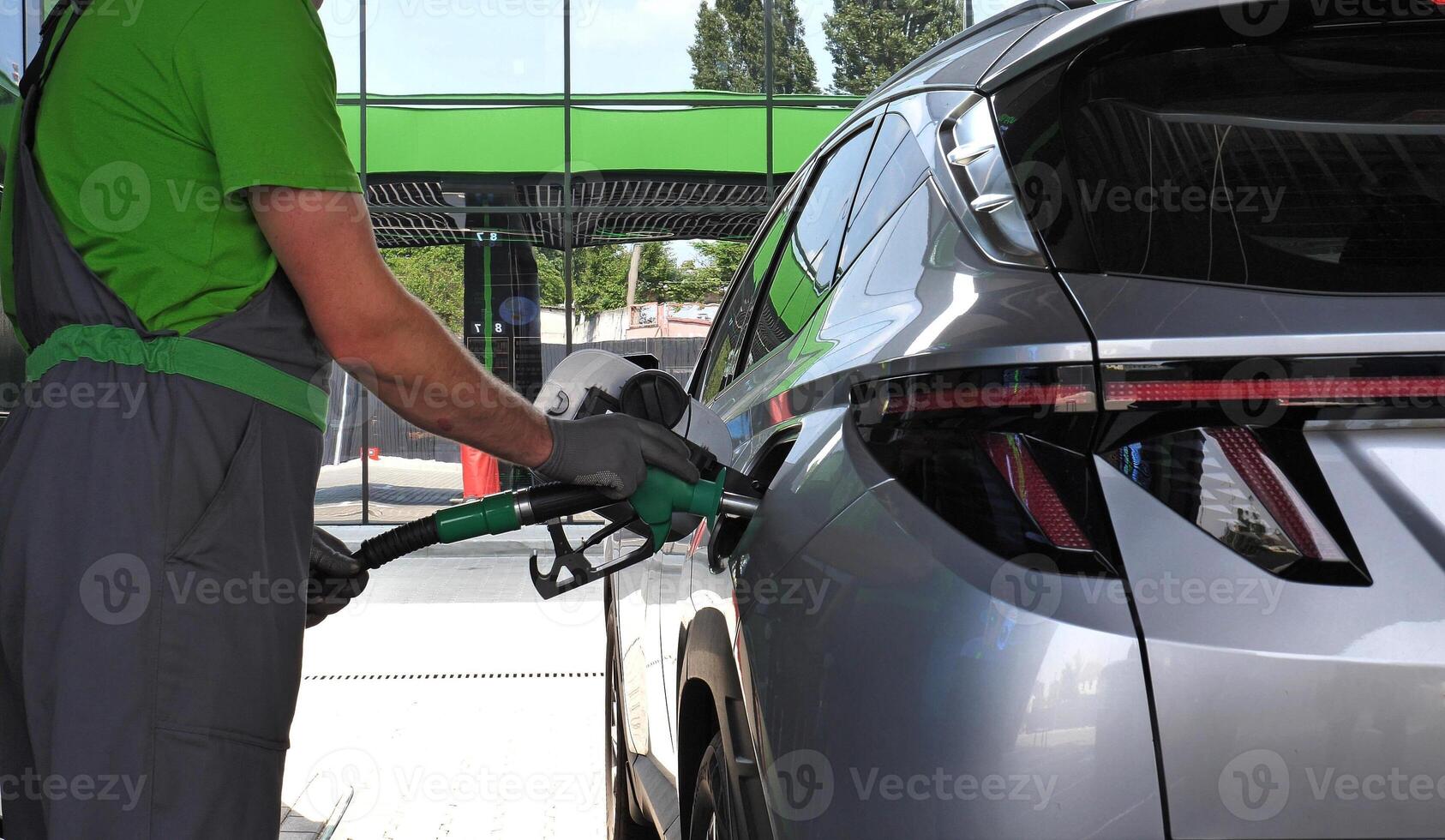 Petrol Station Worker holds a filling nozzle in his hands while refueling a car at a gas station photo