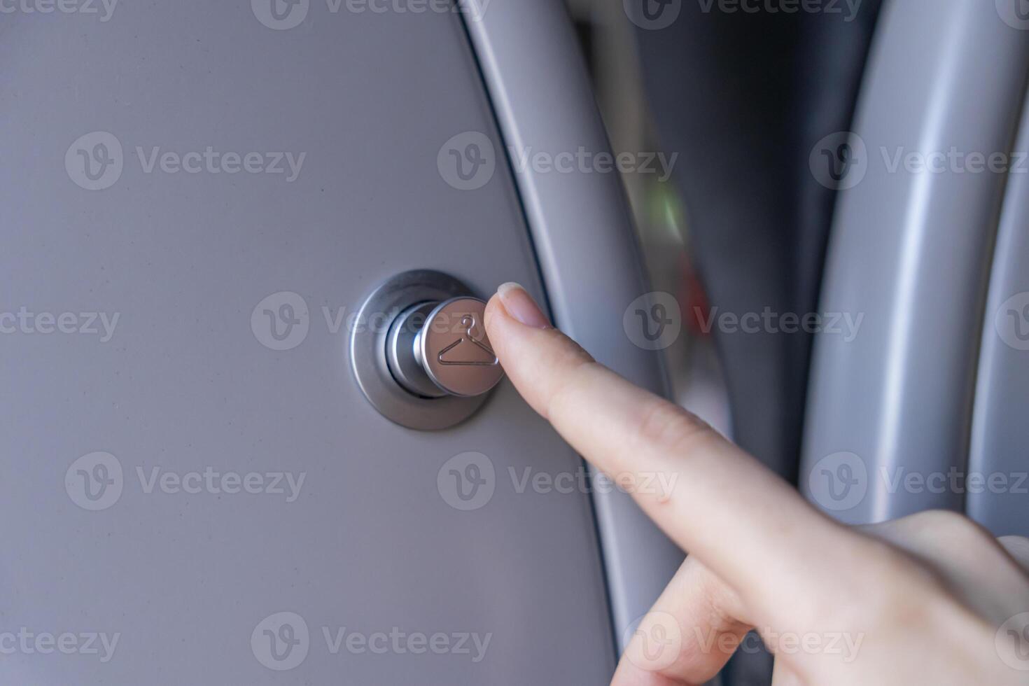 Close-up of a finger pressing a stylish silver button marked with a hanger icon, providing a coat rack or personal storage solution for travelers photo