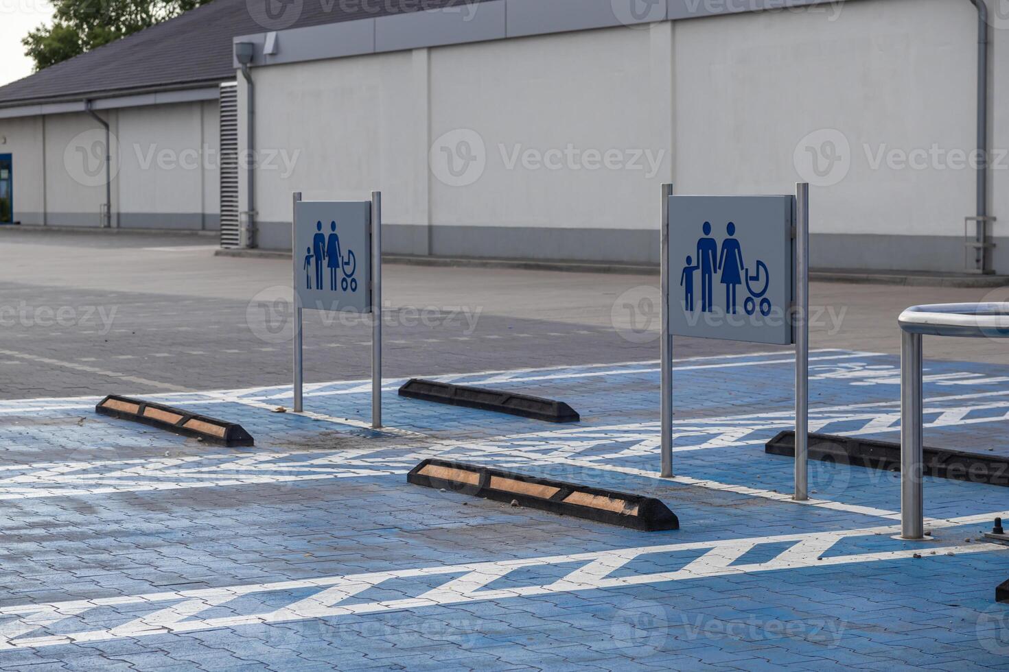 Spacious designated parking spots with blue ground markings and family stroller signs at an empty commercial supermarket lot, symbolizing convenient accessibility photo