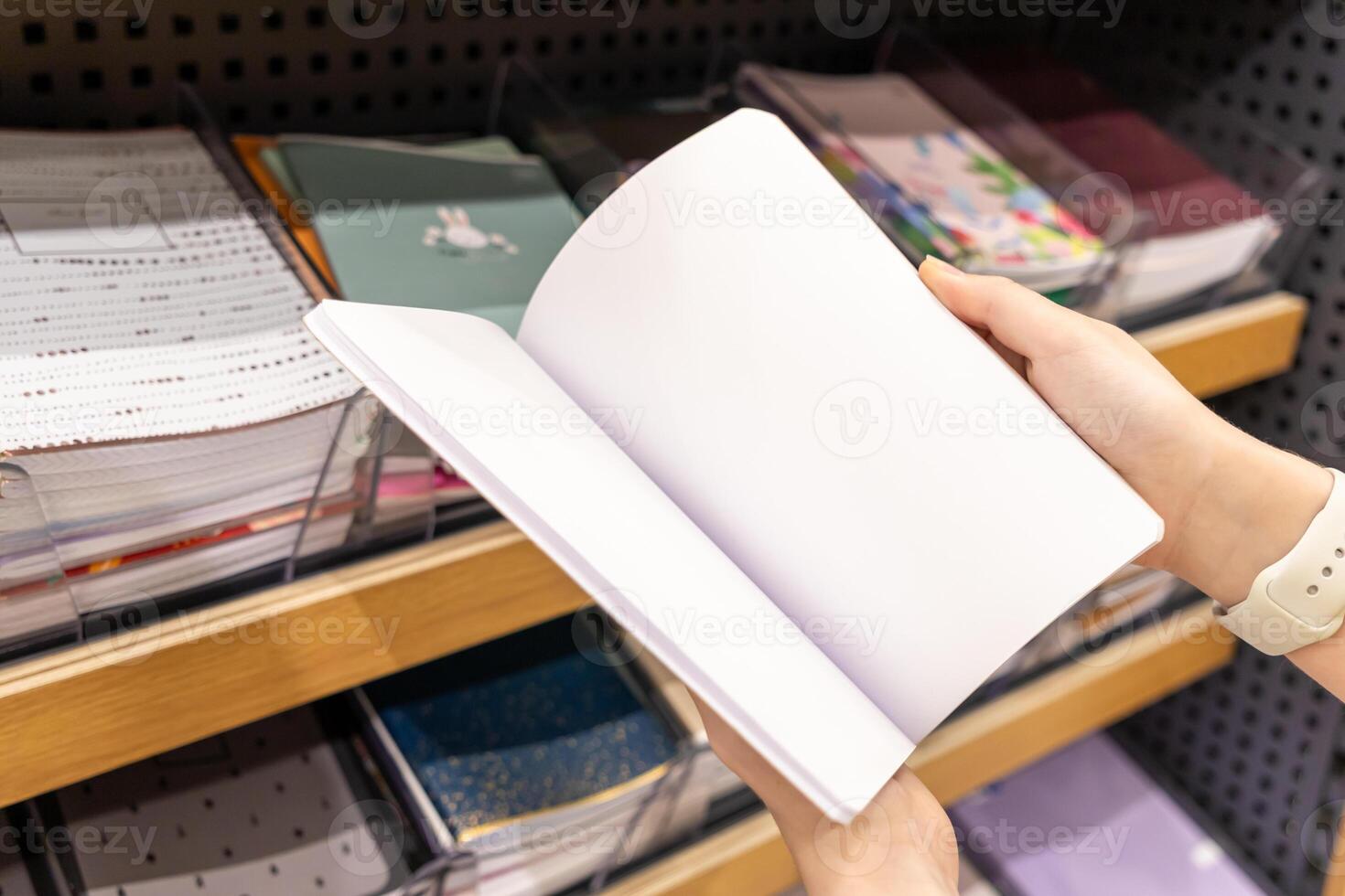 A person's hand holds an open blank white notebook, ready for new concepts, creative expression, or educational studies in a retail environment photo