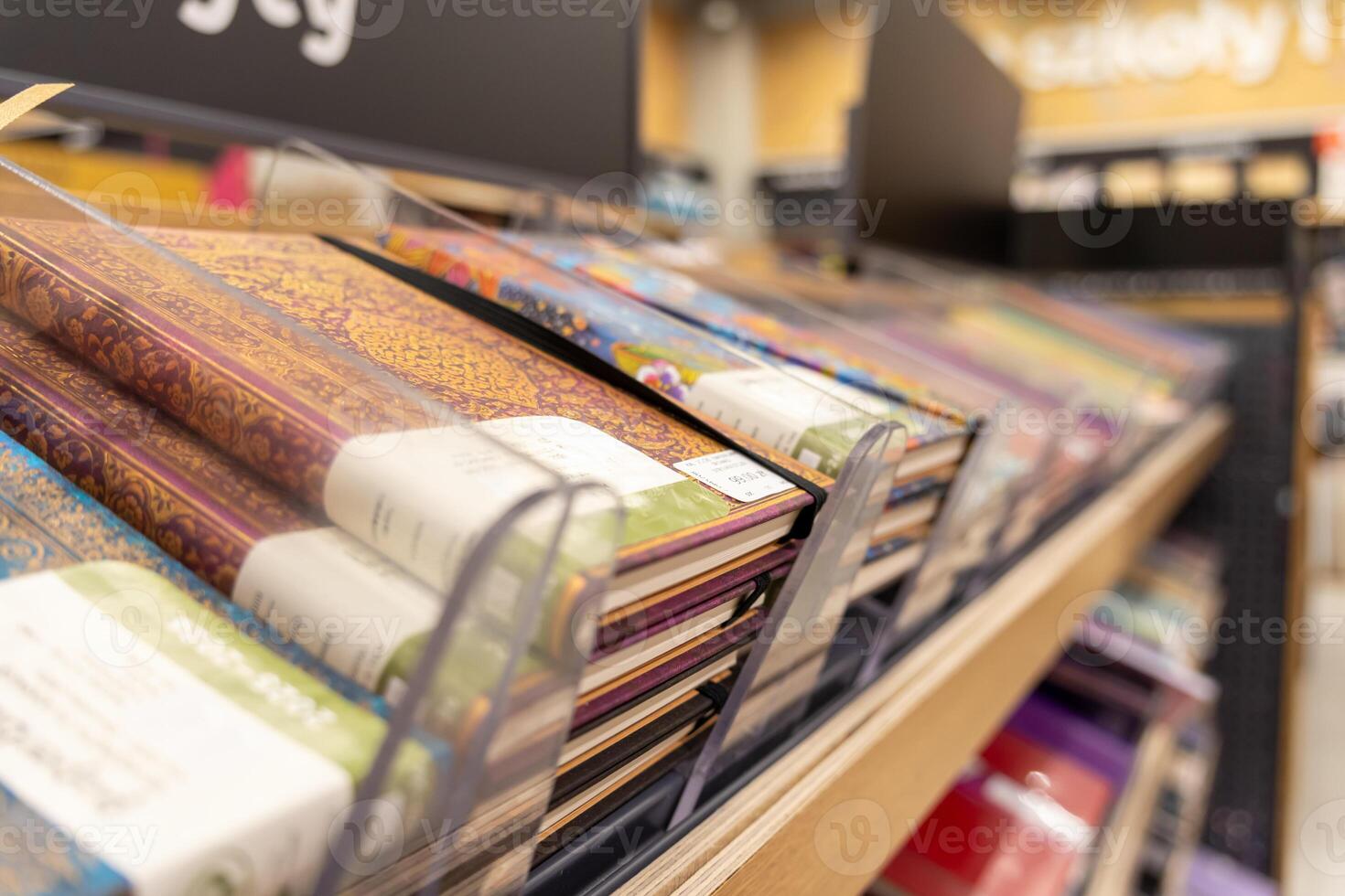 Abundant selection of vibrant, decorative notebooks neatly displayed on a retail store shelf, providing essential stationery for educational and professional use photo