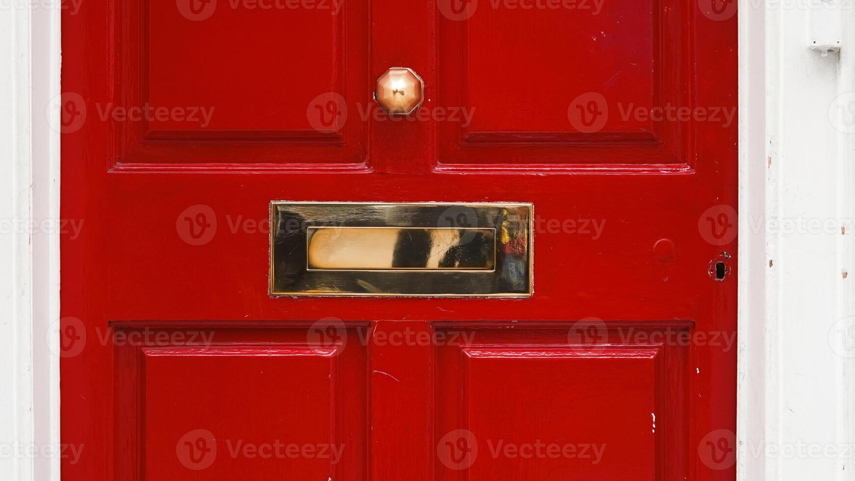 Architectural fragment of English home red door with vintage mail slot and handle photo