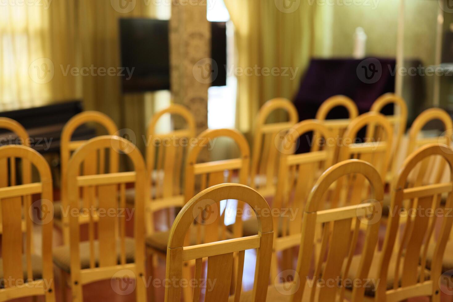 The area has neatly arranged empty chairs ready for an event in a simple, spacious hall photo