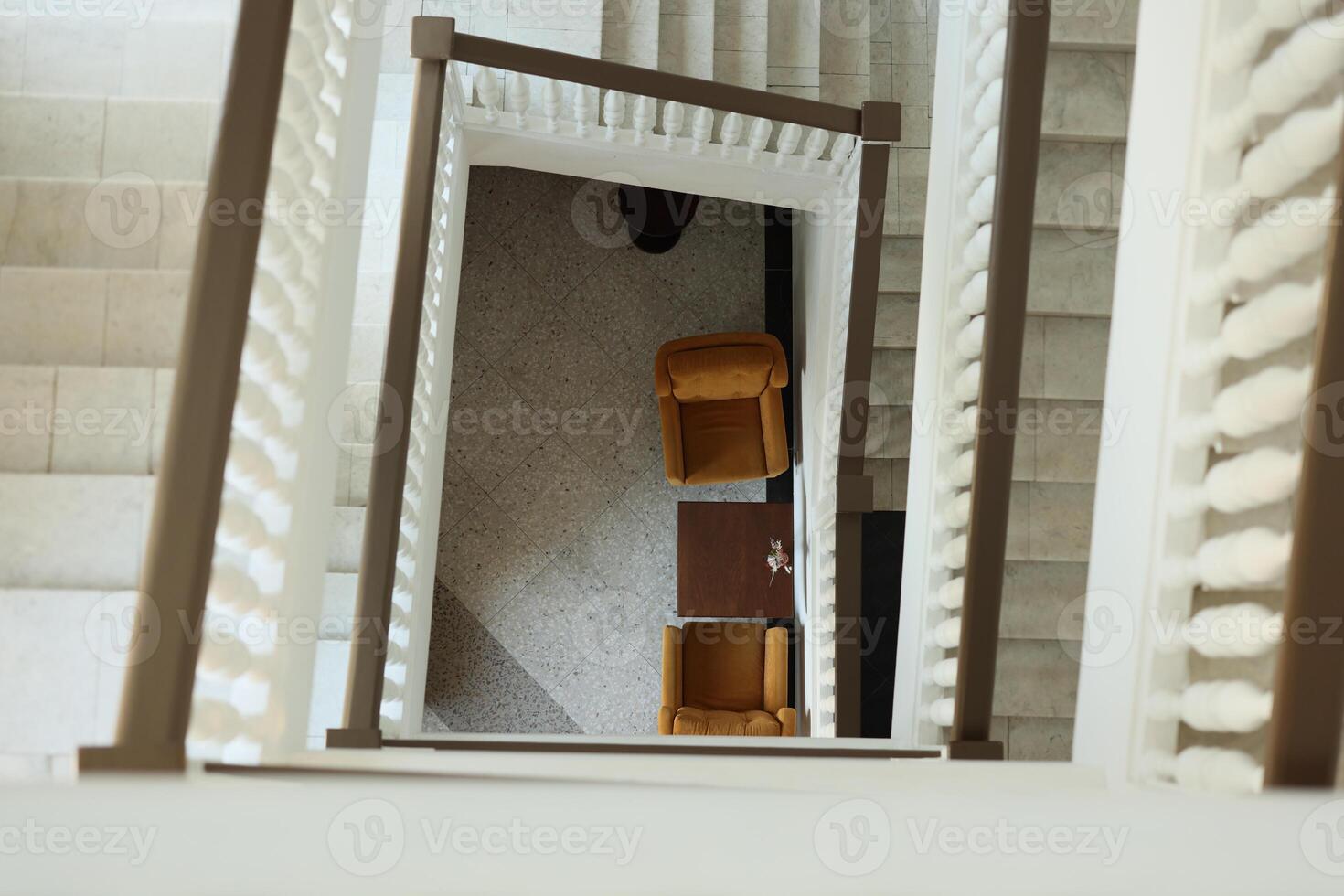 Captivating View from Above A Beautiful Staircase Presenting Chairs and a Table photo