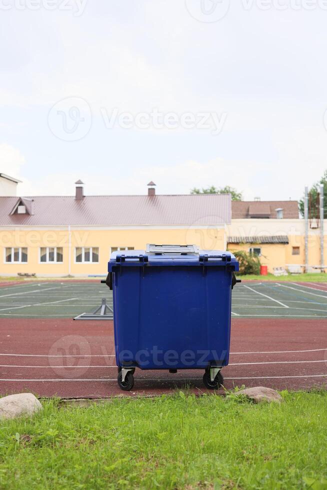 The Blue Trash Bin is prominently located on the Sports Field adjacent to the School Building photo