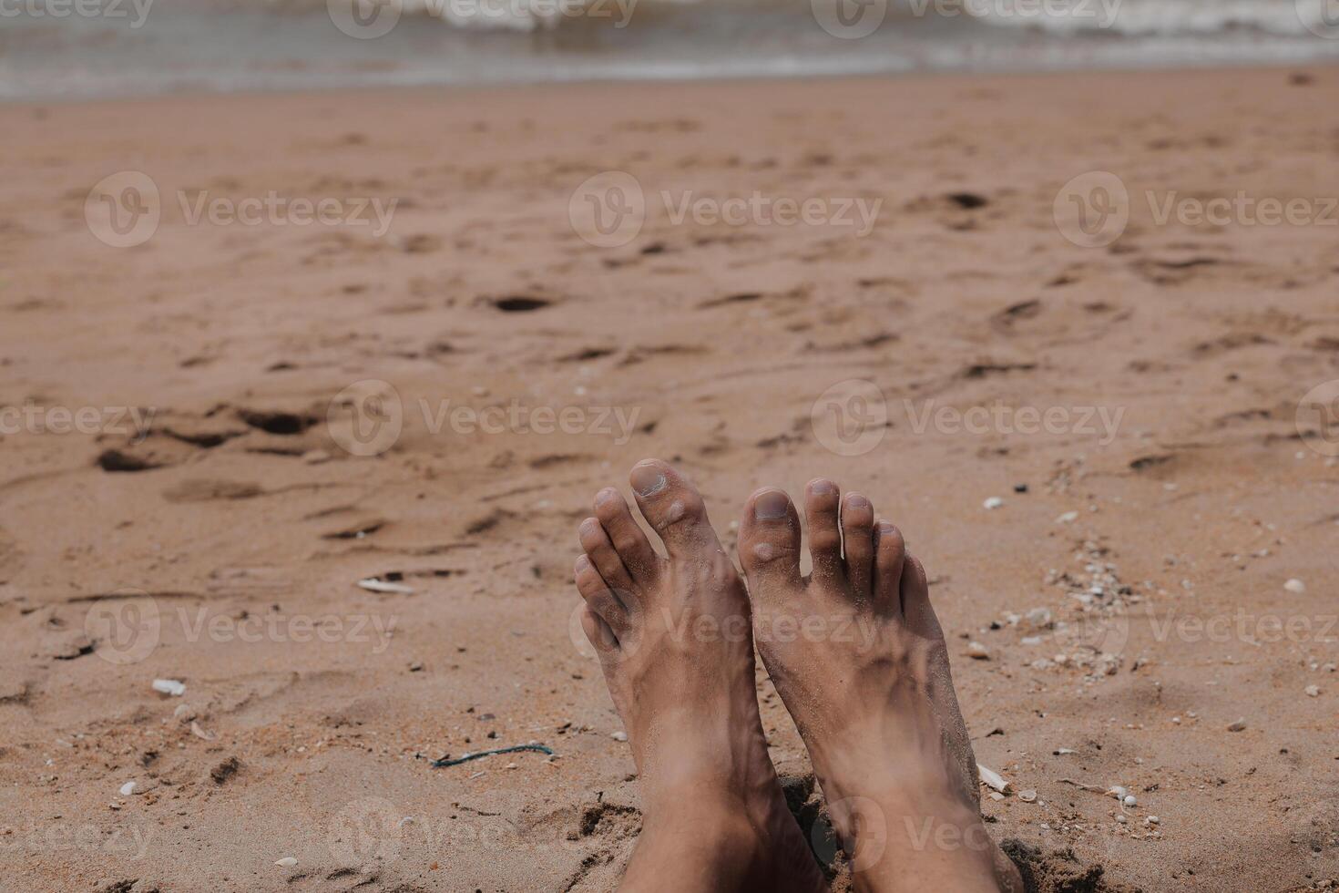 Enjoy a serene experience of relaxing your feet on the sandy beach beside the ocean waves photo