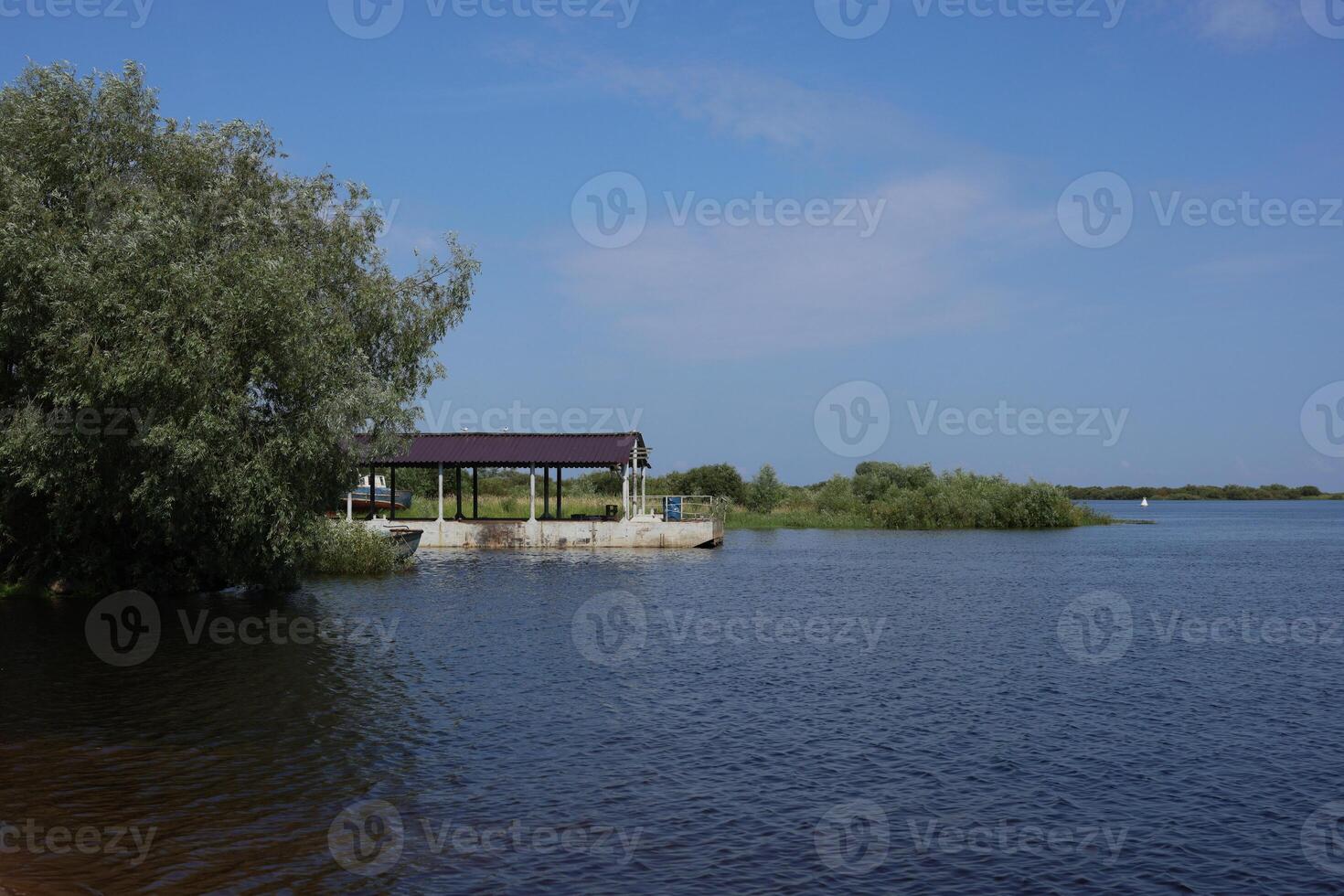 A Beautiful Scenic Waterfront View with a Shelter Surrounded by Lush and Vibrant Vegetation photo