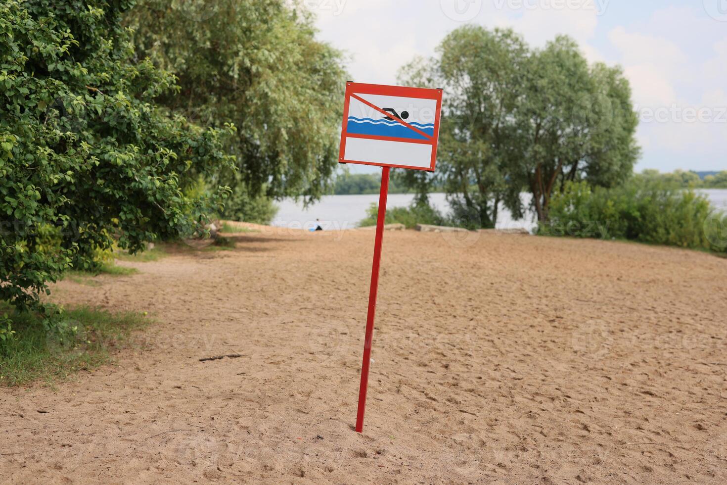 Cautionary Warning Sign Present at Sandy Beach that is Located Near the Water Body Area photo