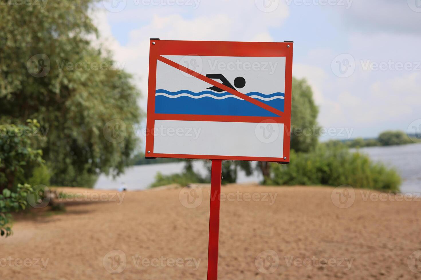A sign indicating that swimming is prohibited at a beautiful lakefront beach area near water photo