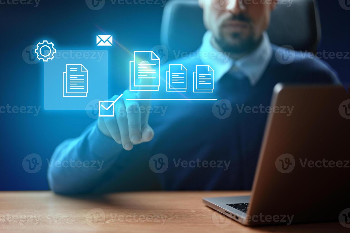 Professional man interacting with digital documents on a laptop at a desk during evening hours photo