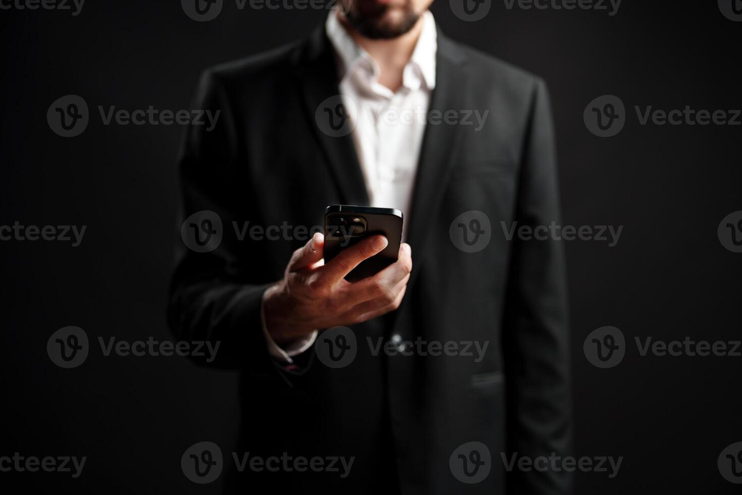 Professional man in formal attire checking smartphone in dimly lit environment photo