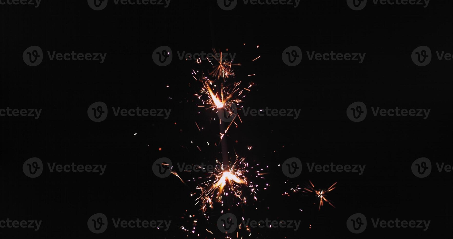 A sparkler is lit up in the dark photo