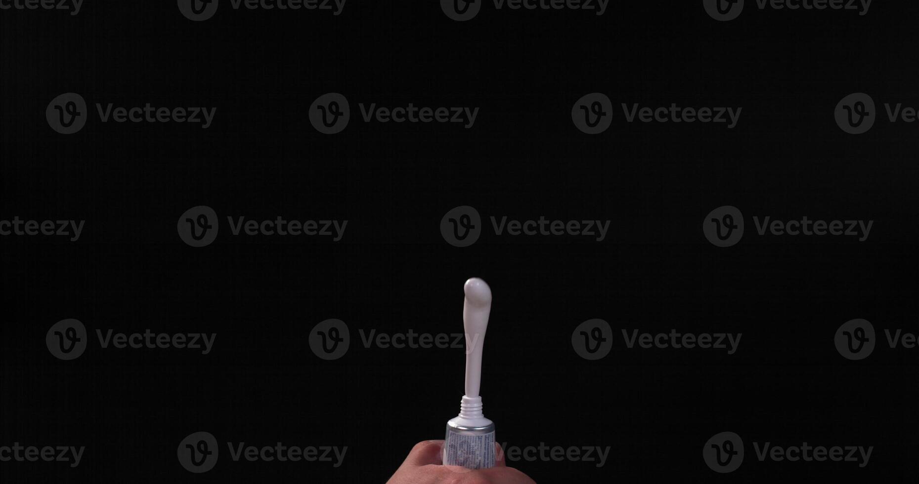 A person holding a toothbrush in front of a black background photo