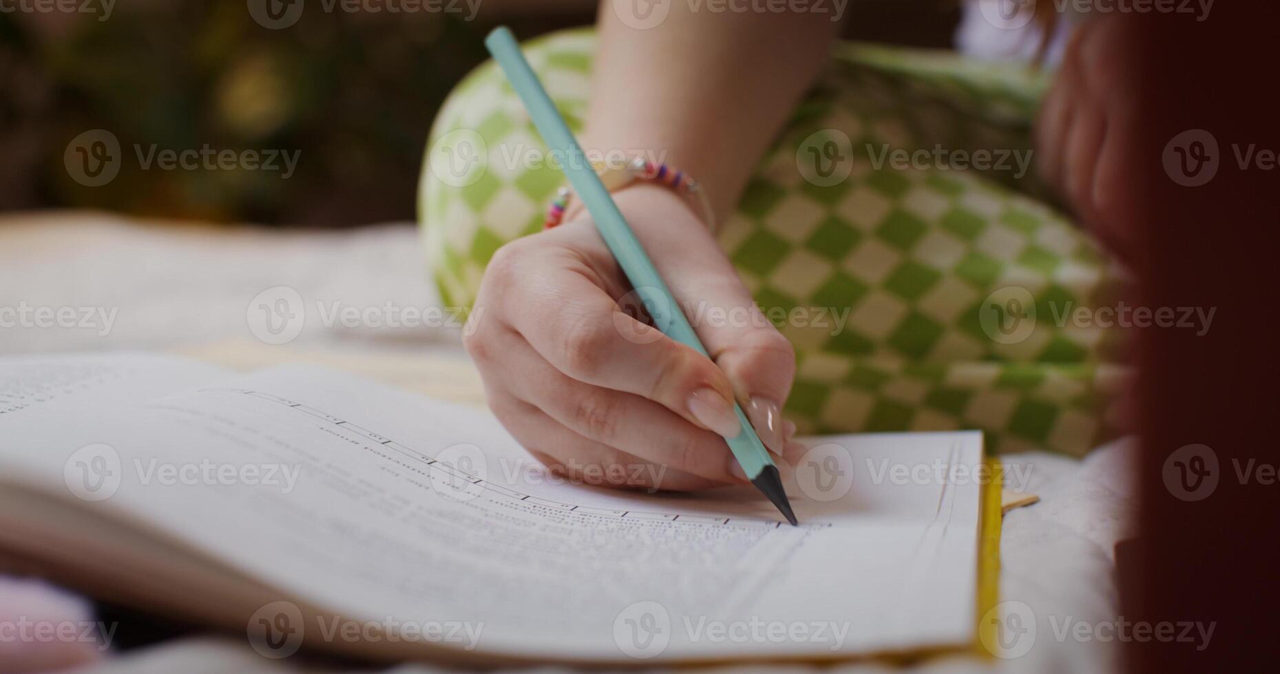 A person is writing on a book with a pencil photo