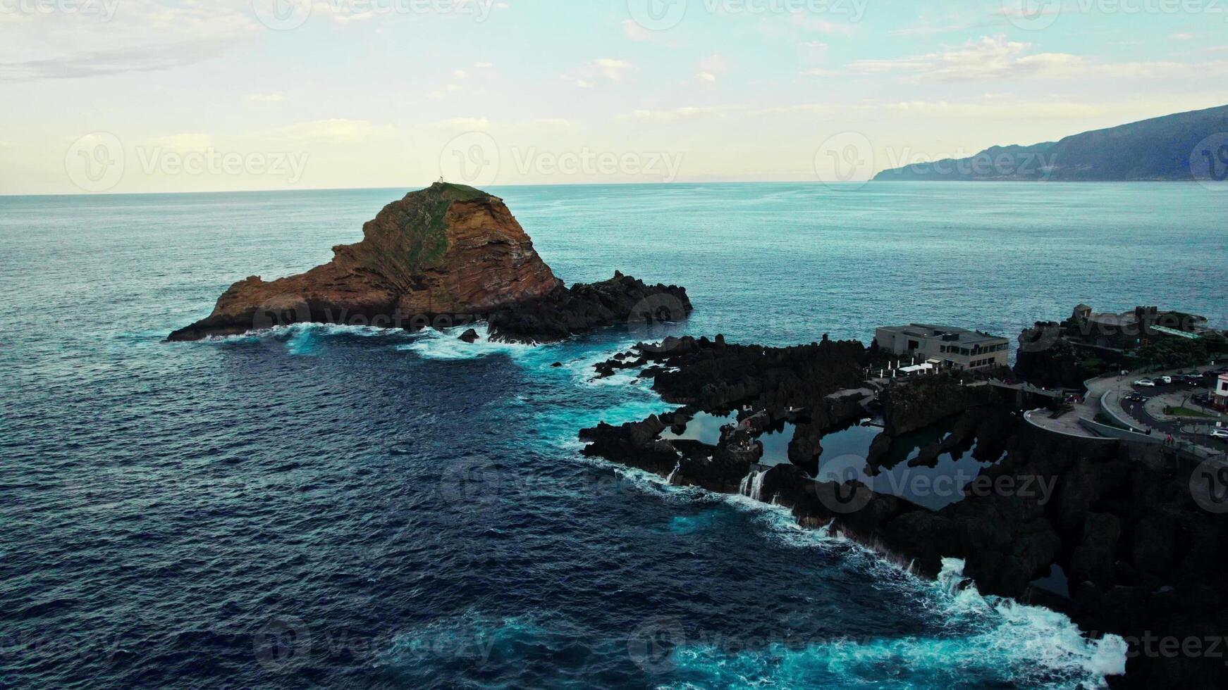 A view of the ocean from above with a lighthouse in the distance photo