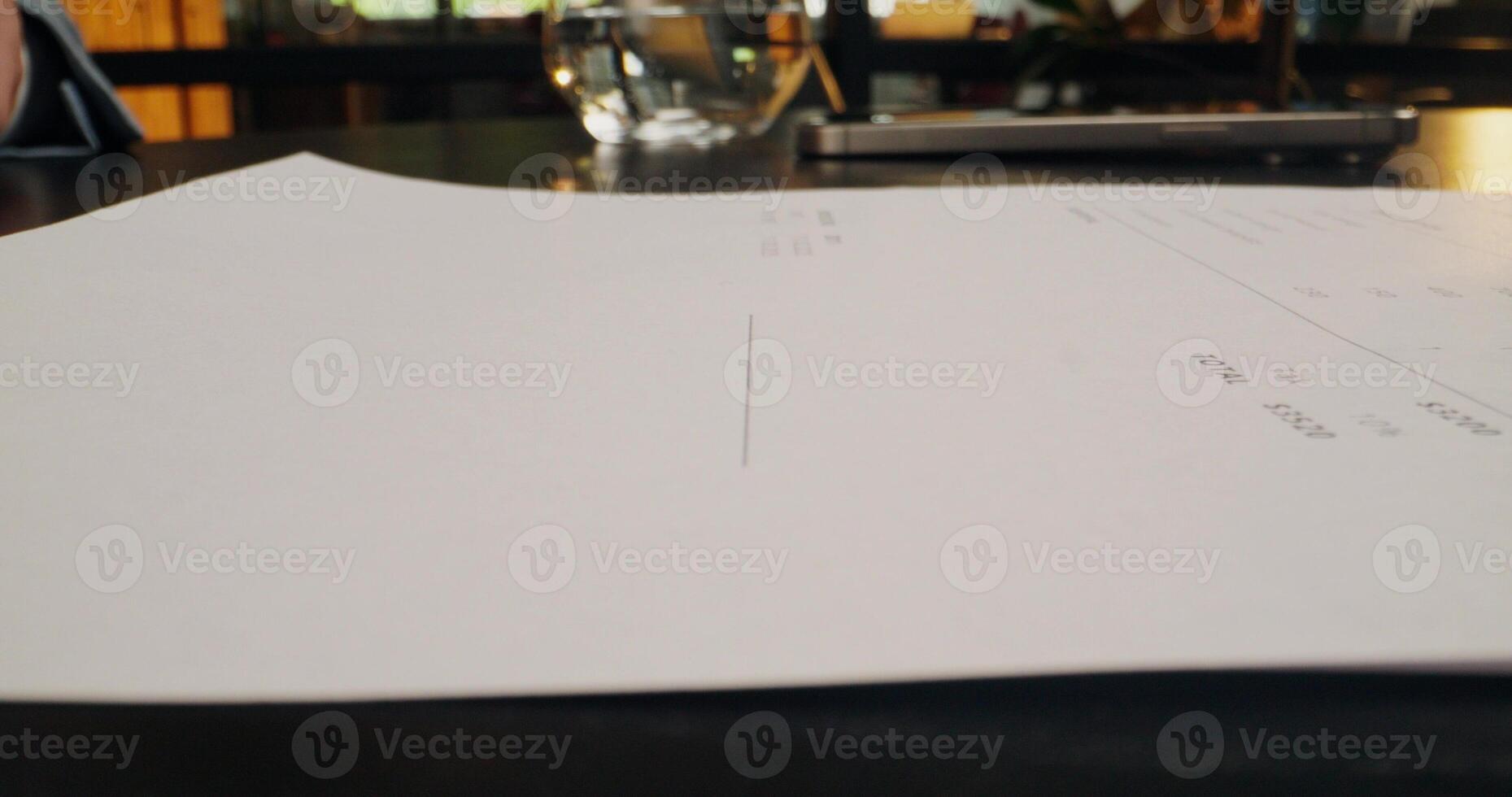 A white paper on a table with a pen photo